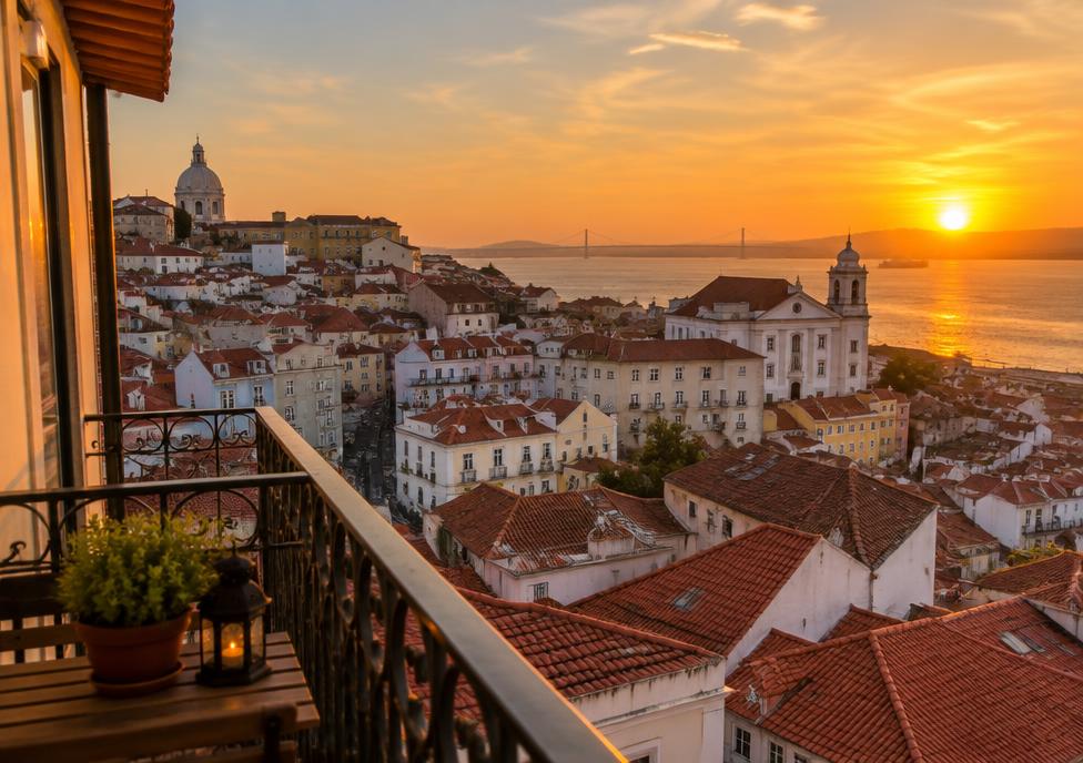 Sunset over Lisbon rooftops from a balcony
